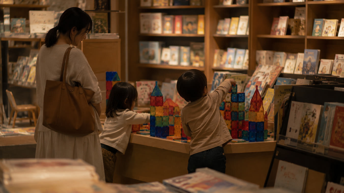 書店の児童書コーナーで、ブロック遊びに夢中の子どもたちと見守る母親
