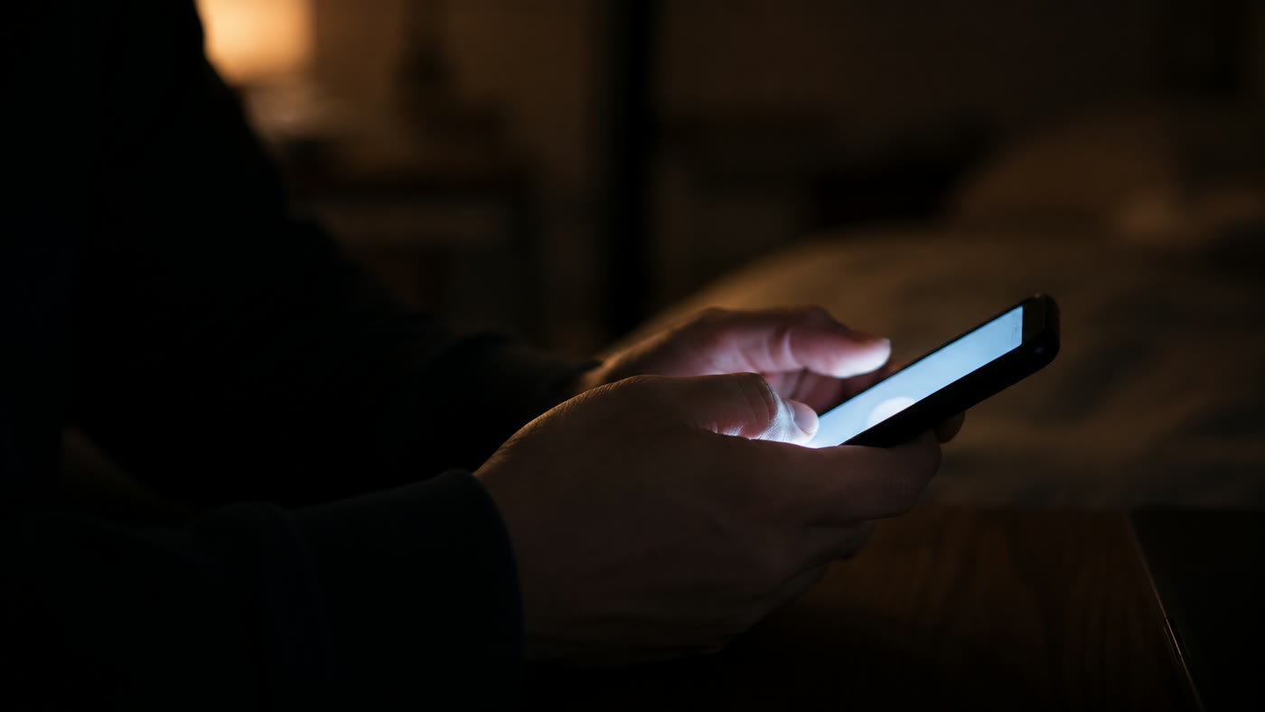 夜、スマートフォンを操作する手元